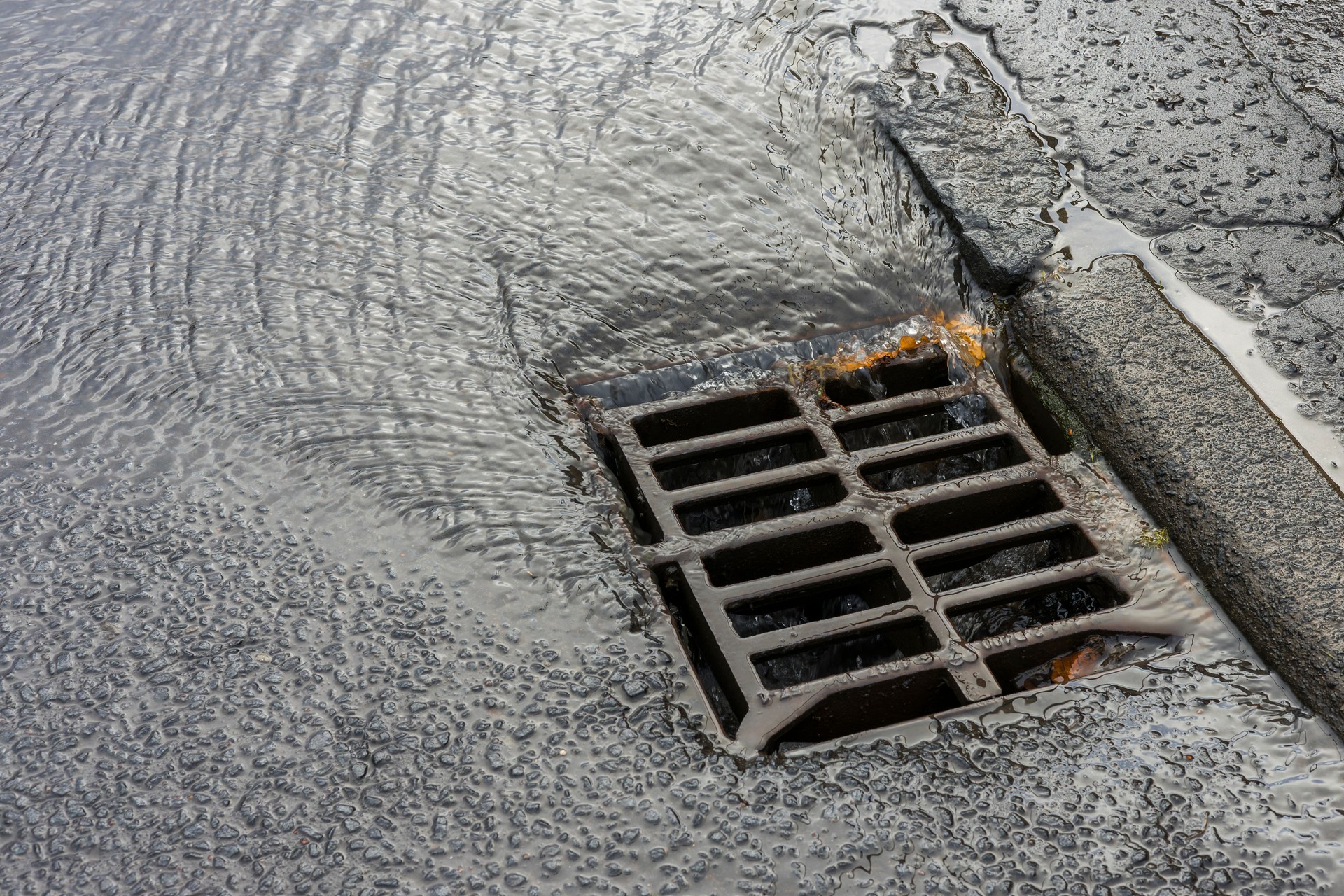 Flood from Burst Water Main Flowing Along Road into Storm Drain Sewer at Street Kerbside